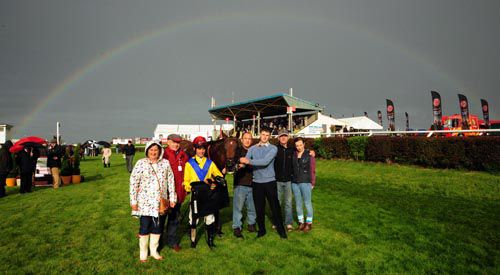 Connections of All Ablaze gather under a rainbow in the winners' enclosure 