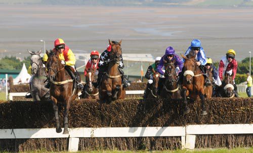 Bachelor Affair (left, yellow sleeves) jumps a fence  with a view of Tramore's bay in the background