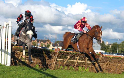 Blue Vic (right) and Tim Carroll jump the last alongside Magnetic Force in the two mile handicap hurdle