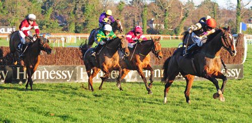 On His Own leads the field over the second last with Road To Riches (maroon) in the centre  