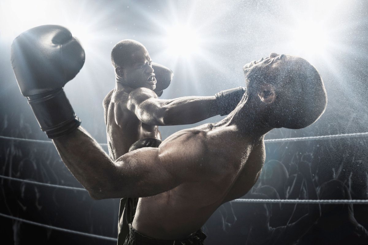 D2PKKJ African American boxer hitting opponent in boxing ring